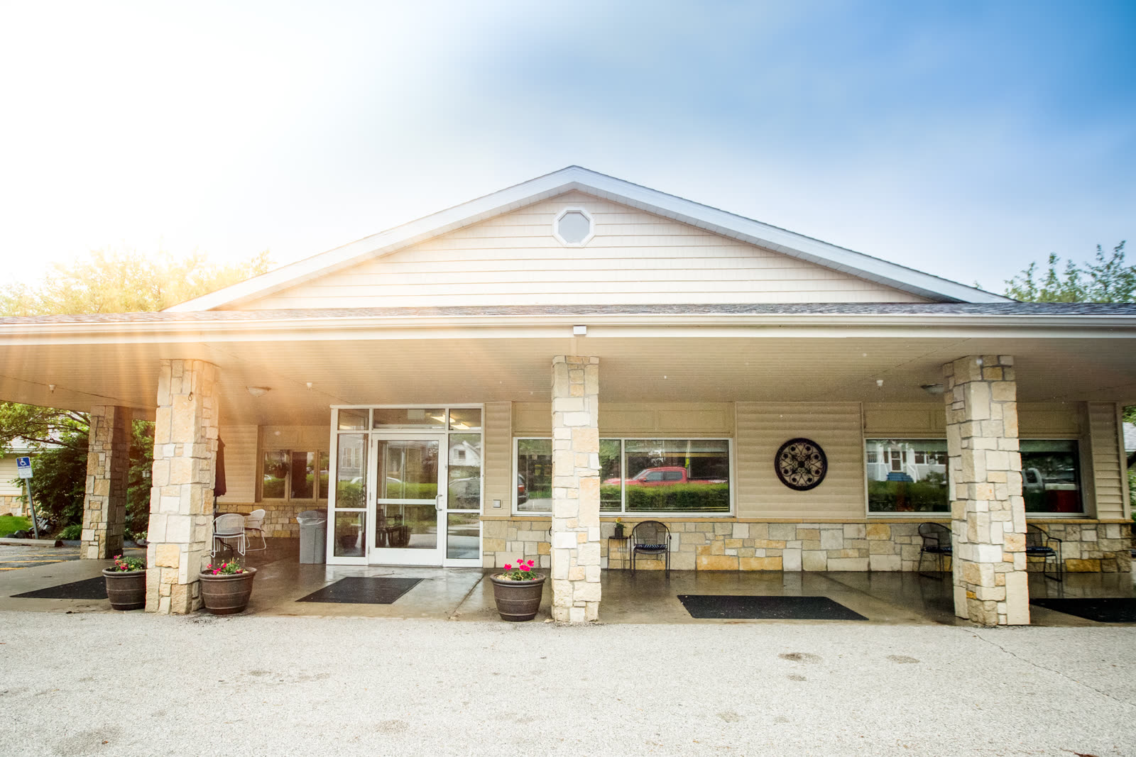 The welcoming covered front entrance of The Ivy at Davenport Nursing & Rehabilitation, with stone columns and flower planters