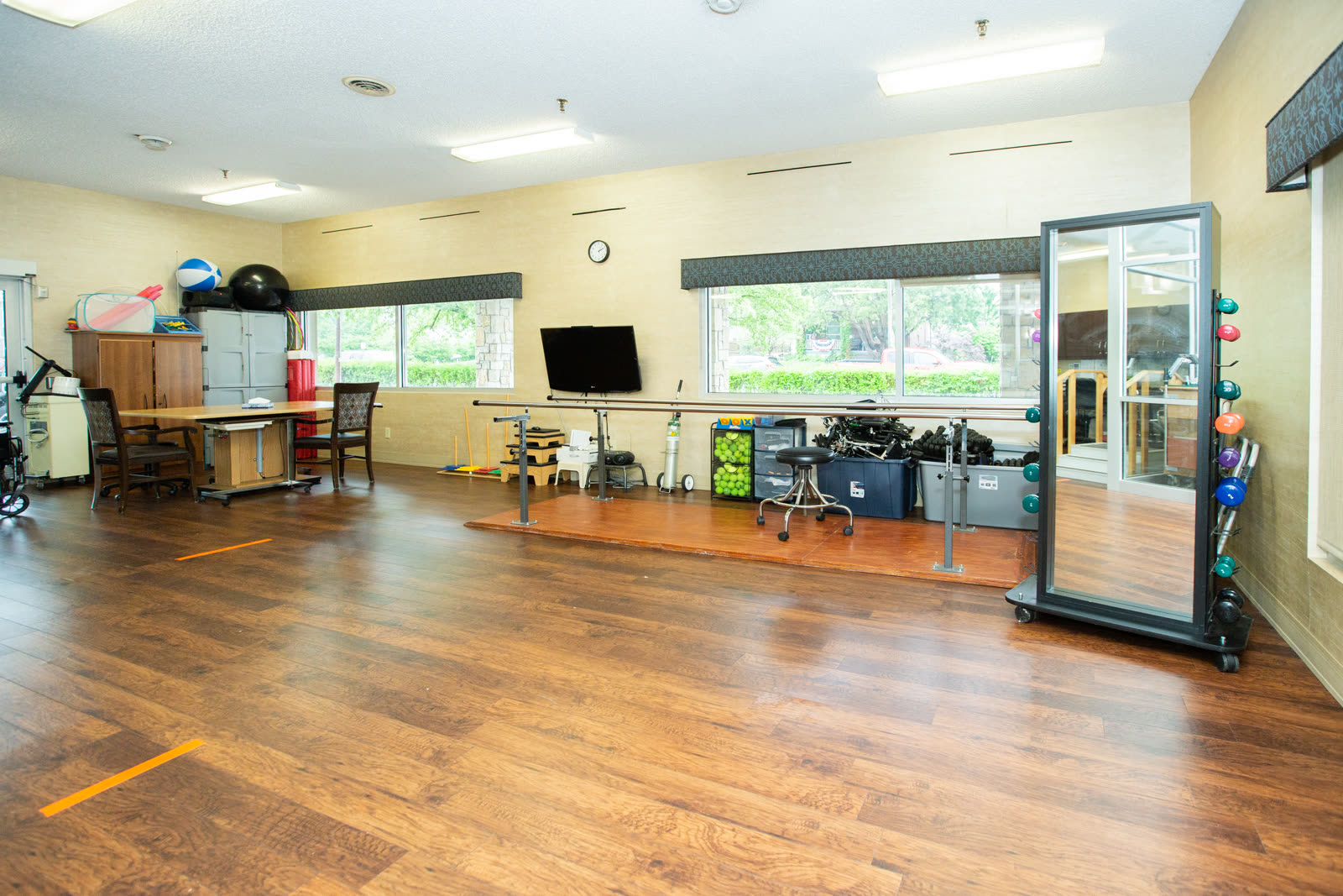 The bright, fully equipped on-site physical therapy gym at The Ivy at Davenport with hardwood floors and large windows